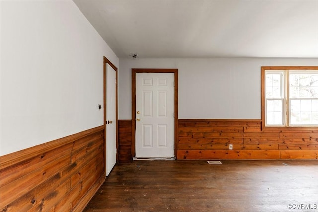 empty room featuring a wainscoted wall, dark wood-style floors, and wood walls