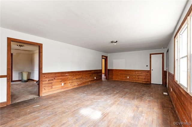 empty room featuring wainscoting, wooden walls, and hardwood / wood-style floors