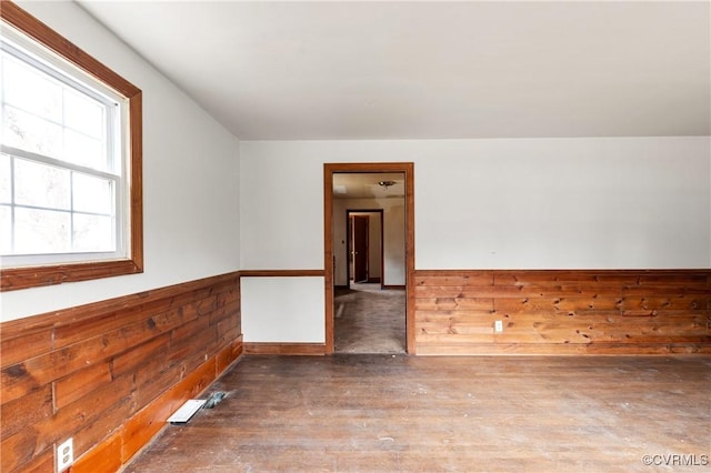 unfurnished room featuring a wainscoted wall, wood finished floors, visible vents, and wooden walls