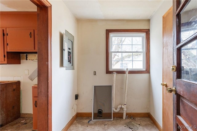 clothes washing area with electric panel and baseboards