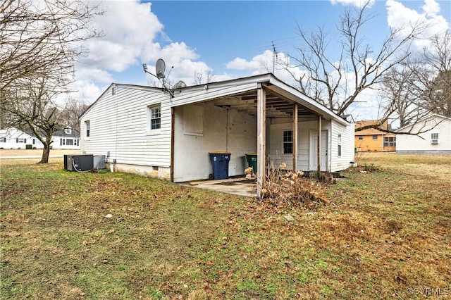 rear view of property with crawl space, central AC, and a yard