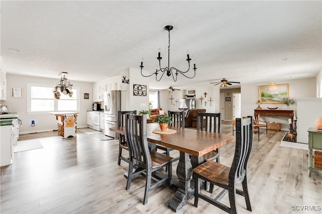 dining room featuring ceiling fan with notable chandelier, baseboards, and light wood-style floors