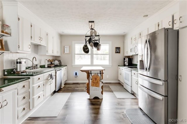 kitchen featuring a sink, tasteful backsplash, dark countertops, white cabinetry, and appliances with stainless steel finishes