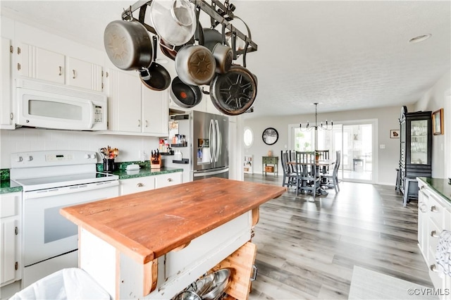 kitchen with white appliances, light wood-style flooring, decorative backsplash, white cabinets, and pendant lighting