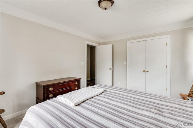 carpeted bedroom with a closet, crown molding, and baseboards