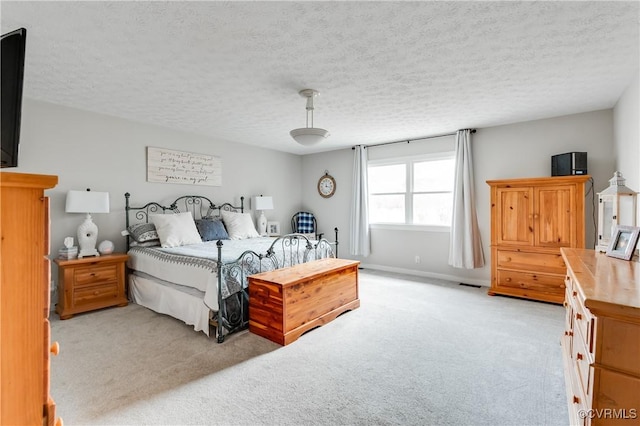 bedroom featuring light carpet, visible vents, a textured ceiling, and baseboards