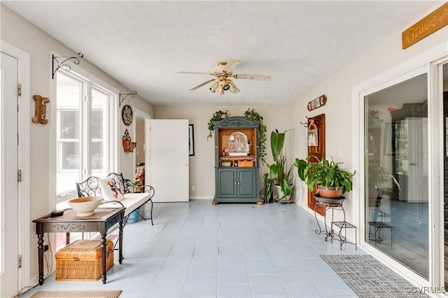 interior space with tile patterned floors, a textured ceiling, and ceiling fan