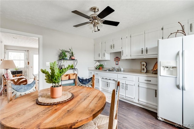 kitchen with dark wood finished floors, light countertops, white refrigerator with ice dispenser, white cabinets, and a textured ceiling