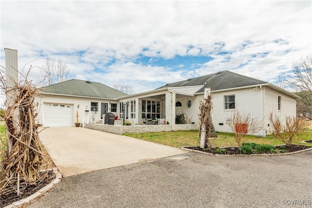 single story home featuring a front yard, brick siding, concrete driveway, and an attached garage