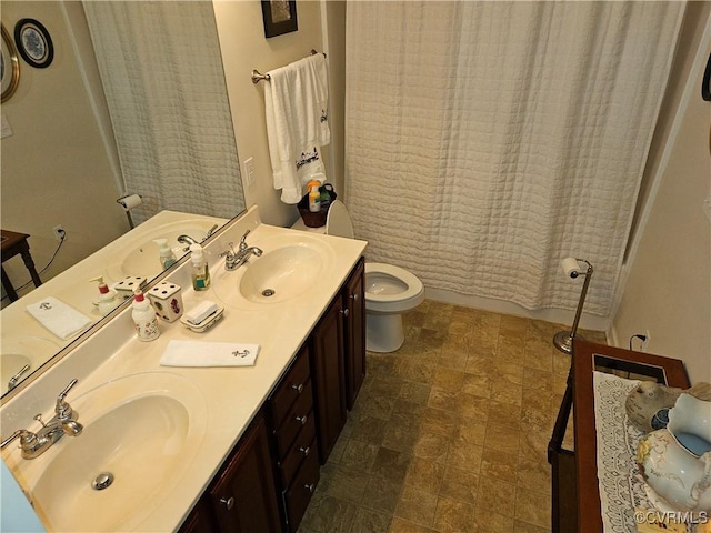 full bath featuring double vanity, a sink, and toilet