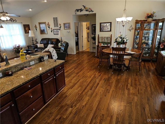 kitchen featuring stone countertops, vaulted ceiling, dark wood-type flooring, and ceiling fan with notable chandelier