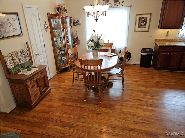 dining space featuring baseboards, an inviting chandelier, and wood finished floors