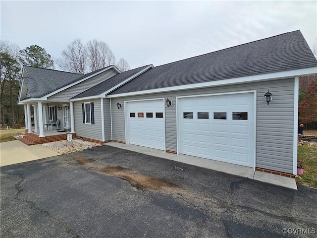 view of front of home featuring a garage, covered porch, a shingled roof, and aphalt driveway