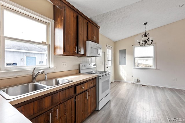 kitchen featuring a textured ceiling, white appliances, a sink, light countertops, and decorative backsplash