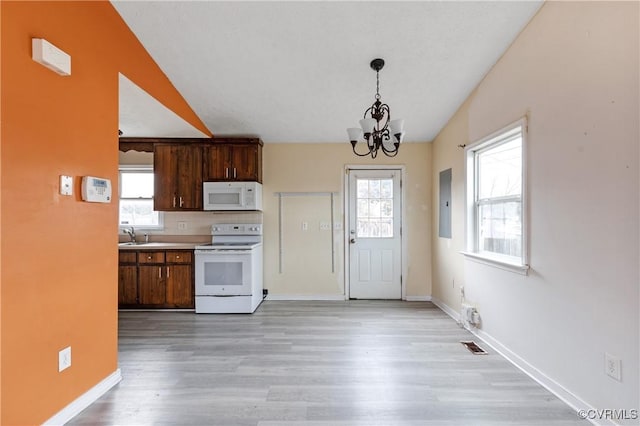 kitchen featuring white appliances, a notable chandelier, light wood finished floors, and a wealth of natural light