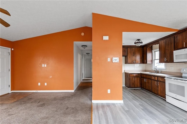 kitchen featuring lofted ceiling, white appliances, baseboards, light countertops, and decorative backsplash