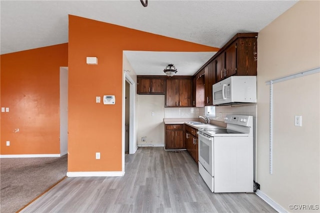 kitchen with lofted ceiling, white appliances, a sink, light countertops, and tasteful backsplash