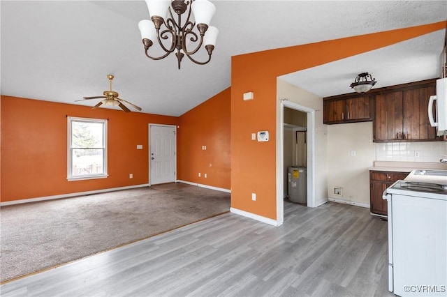 kitchen with decorative backsplash, white microwave, vaulted ceiling, range, and baseboards