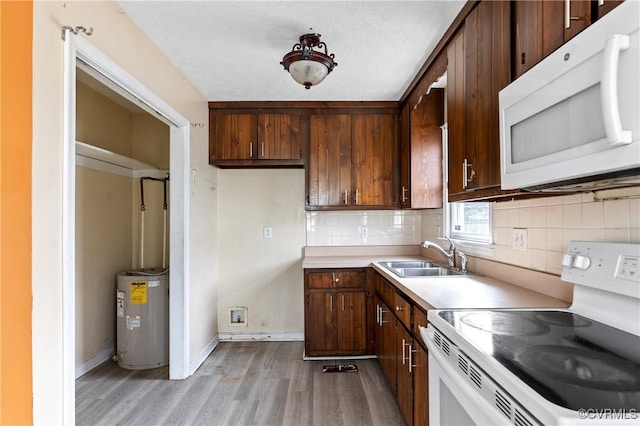 kitchen featuring white appliances, tasteful backsplash, light countertops, water heater, and a sink