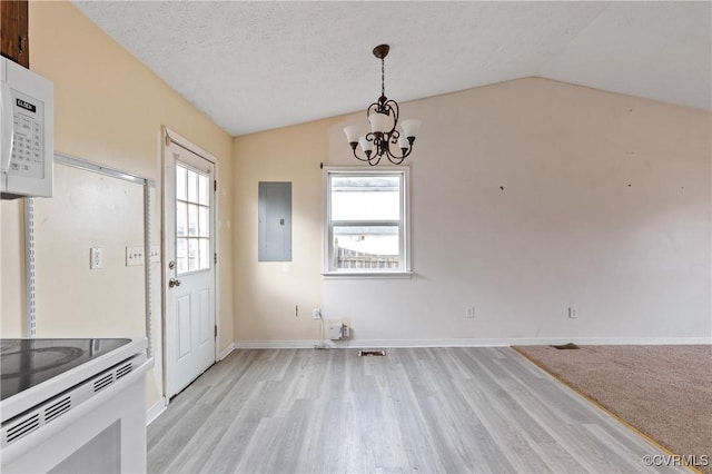 unfurnished dining area with lofted ceiling, electric panel, a textured ceiling, and an inviting chandelier