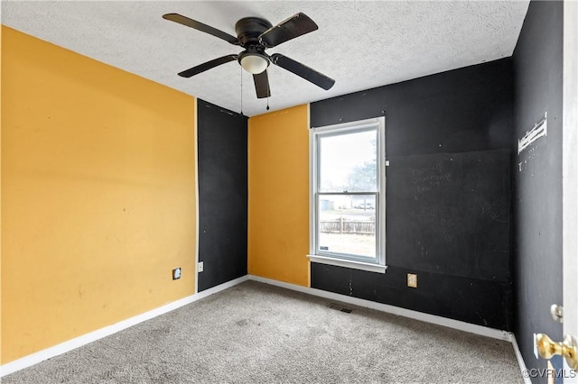 carpeted empty room with a textured ceiling, ceiling fan, visible vents, and baseboards