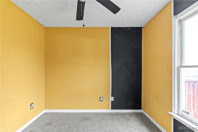 empty room featuring a textured ceiling, carpet, a ceiling fan, and baseboards