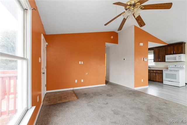 unfurnished living room featuring lofted ceiling, baseboards, a ceiling fan, and light colored carpet