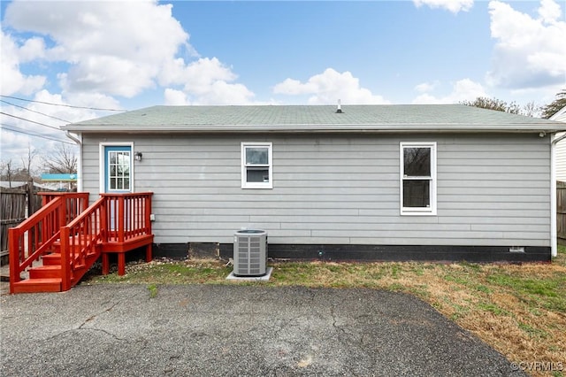 rear view of property featuring a patio area, a shingled roof, fence, and central AC unit