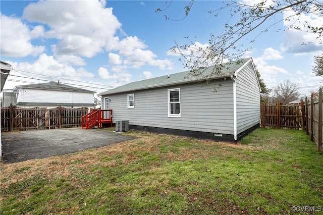 back of house featuring central AC unit, a fenced backyard, crawl space, a yard, and a patio area