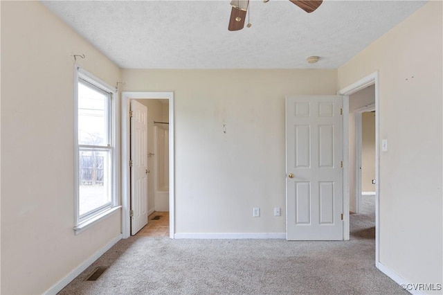 unfurnished bedroom with carpet, visible vents, a textured ceiling, and baseboards