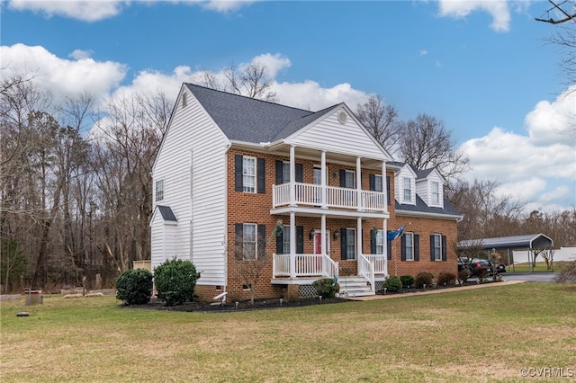 neoclassical home with brick siding, a porch, a front yard, and a balcony