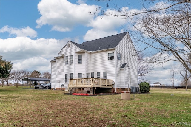 rear view of property featuring central AC unit, roof with shingles, a deck, a yard, and a detached carport