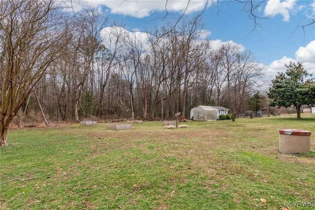 view of yard with a garden, a greenhouse, and an outdoor structure