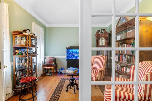 sitting room with crown molding and hardwood / wood-style flooring