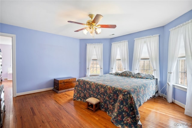 bedroom with light wood finished floors, ceiling fan, visible vents, and baseboards