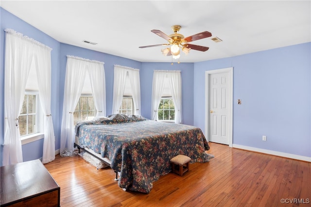 bedroom with a ceiling fan, hardwood / wood-style flooring, visible vents, and baseboards