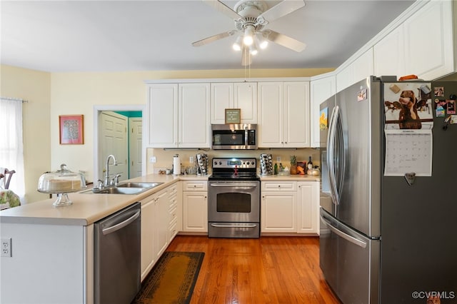 kitchen featuring stainless steel appliances, light countertops, a sink, and a peninsula