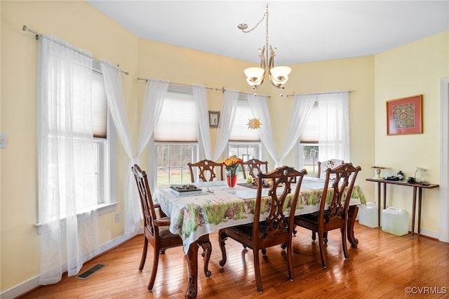 dining area featuring a chandelier, baseboards, visible vents, and hardwood / wood-style floors