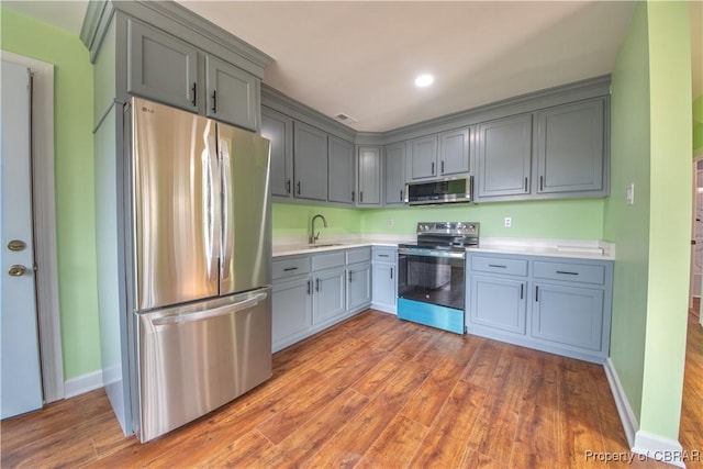 kitchen with appliances with stainless steel finishes, gray cabinets, light countertops, and a sink