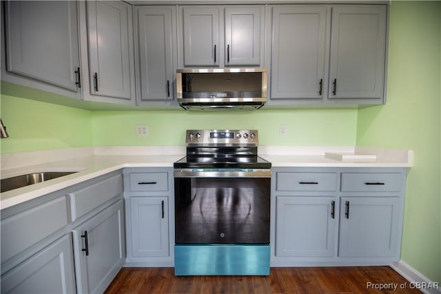 kitchen with appliances with stainless steel finishes, light countertops, dark wood-type flooring, and gray cabinetry