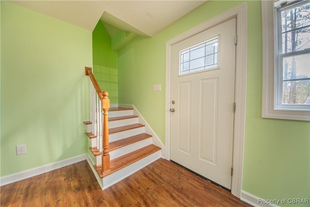 foyer entrance with dark wood-style flooring, a healthy amount of sunlight, and stairway