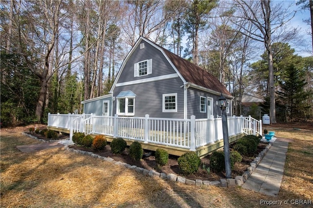 view of home's exterior featuring a deck and a gambrel roof