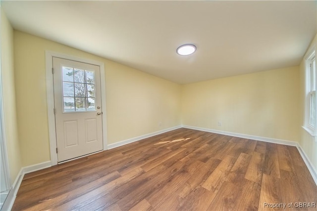 doorway to outside featuring baseboards and wood finished floors