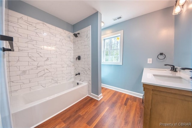 bathroom with baseboards, visible vents, wood finished floors, bathtub / shower combination, and vanity