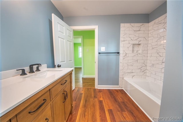 bathroom with shower / tub combination, baseboards, wood finished floors, and vanity