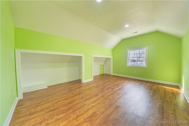 additional living space featuring visible vents, baseboards, vaulted ceiling, and wood finished floors