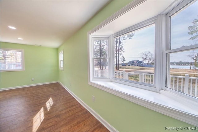 spare room featuring recessed lighting, baseboards, a wealth of natural light, and wood finished floors