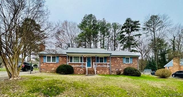 single story home featuring brick siding, a porch, and a front yard