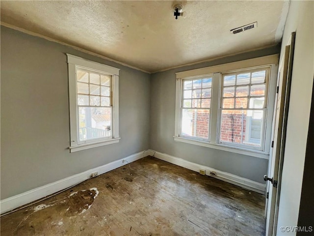 empty room featuring baseboards, visible vents, and a textured ceiling