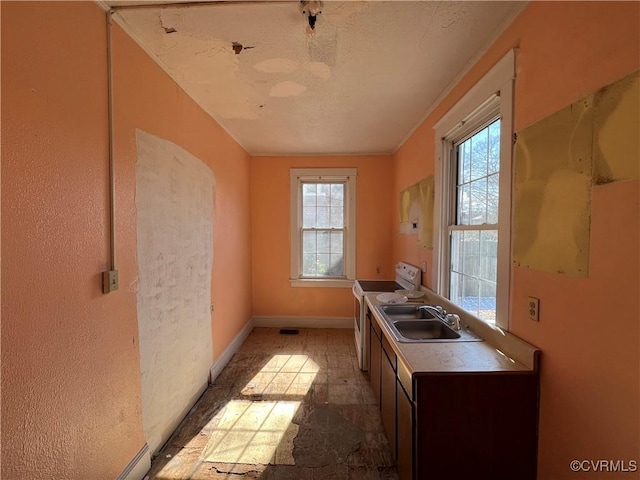 kitchen featuring a textured ceiling, electric range, plenty of natural light, and a sink